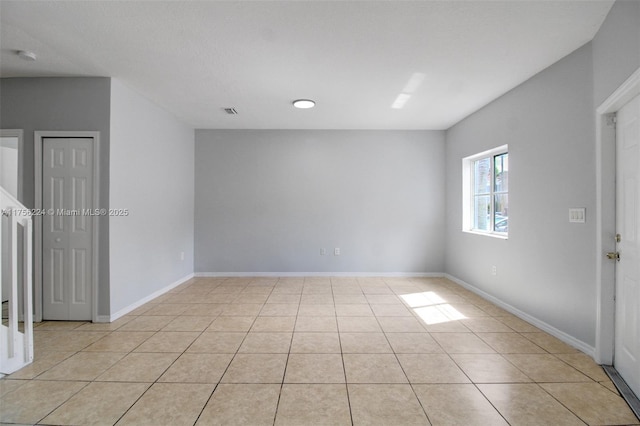 unfurnished room with light tile patterned flooring, visible vents, and baseboards