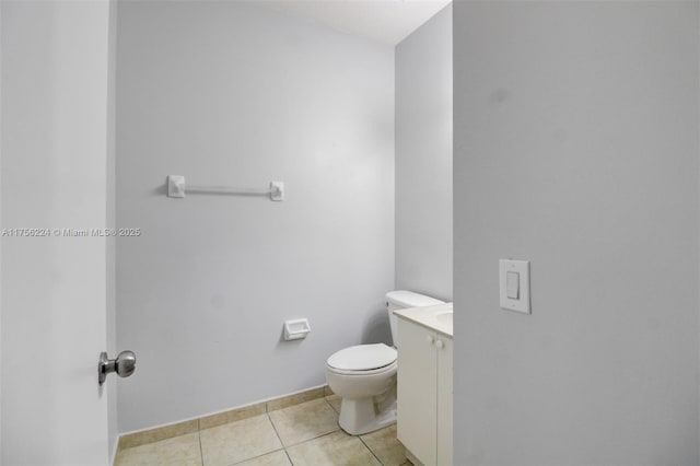 half bathroom featuring toilet, tile patterned flooring, and vanity