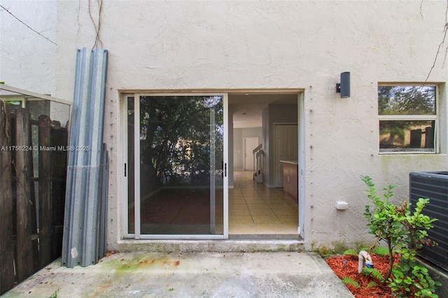 view of exterior entry featuring central air condition unit and stucco siding