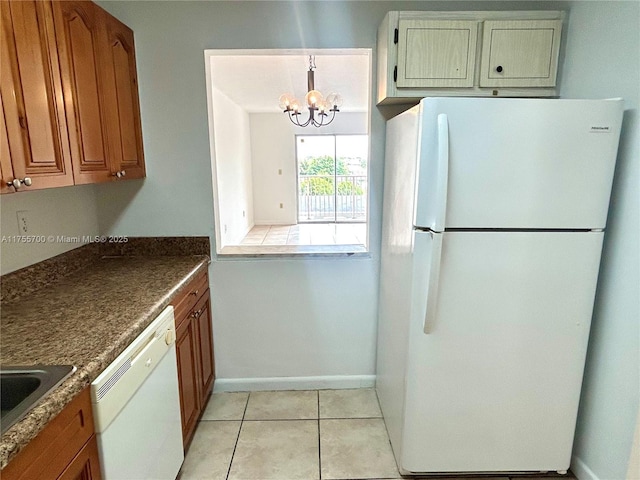 kitchen featuring brown cabinets, white appliances, light tile patterned flooring, and an inviting chandelier