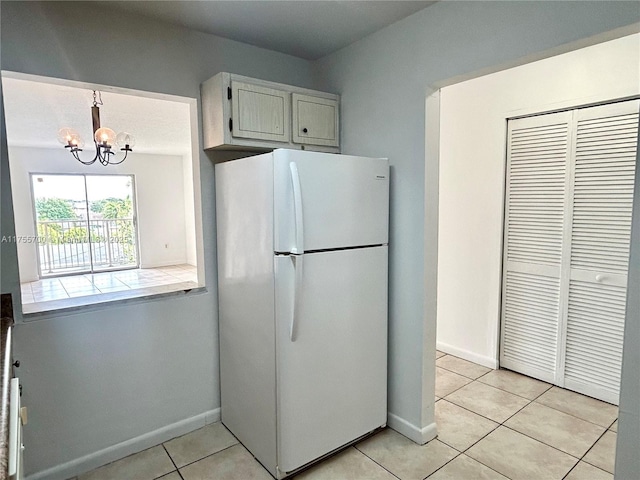 kitchen featuring a notable chandelier, light tile patterned floors, tile counters, freestanding refrigerator, and baseboards