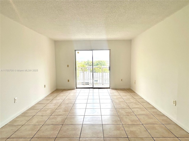 empty room featuring light tile patterned floors, baseboards, and a textured ceiling