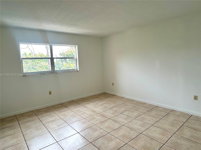 spare room with a textured ceiling and baseboards