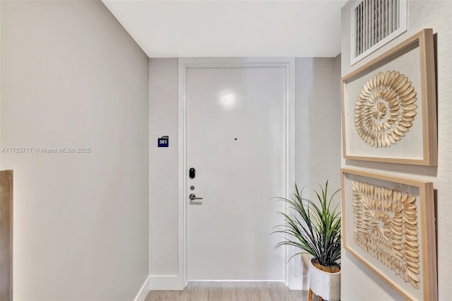 doorway to outside with wood finished floors, visible vents, and baseboards