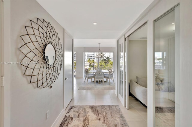 corridor featuring light tile patterned floors and a notable chandelier