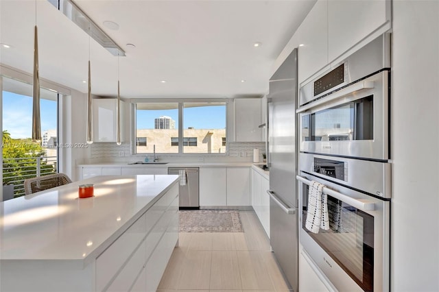 kitchen with light countertops, backsplash, white cabinetry, modern cabinets, and stainless steel appliances