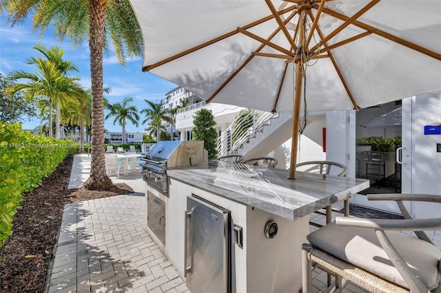 view of patio featuring exterior kitchen and a grill