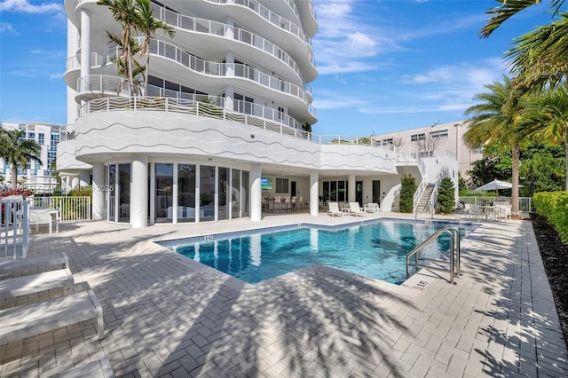 pool with a patio, stairway, and fence