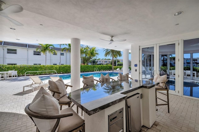 view of patio / terrace featuring an outdoor pool, a ceiling fan, and outdoor dry bar