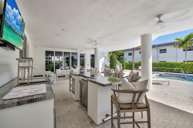 view of patio / terrace featuring area for grilling, ceiling fan, a fenced in pool, and outdoor wet bar