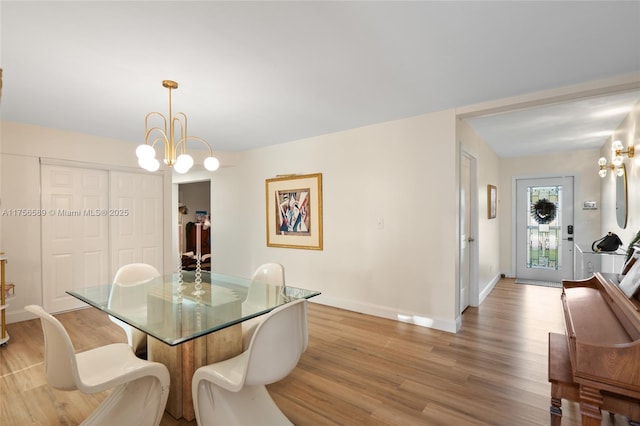 dining room with light wood-style flooring, baseboards, and a notable chandelier