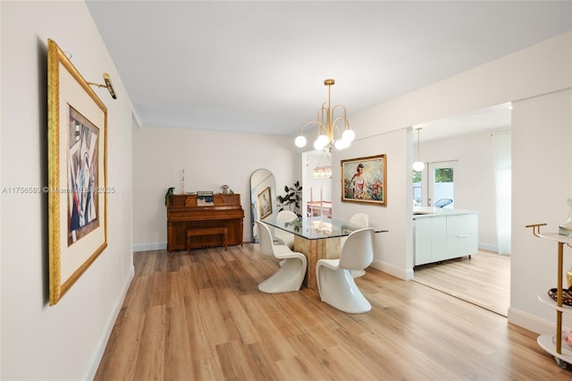 dining room with light wood-type flooring, an inviting chandelier, and baseboards