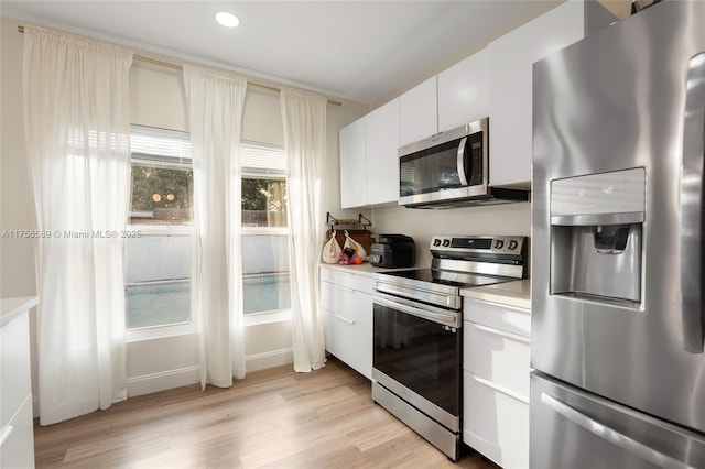 kitchen featuring light wood-style flooring, appliances with stainless steel finishes, light countertops, white cabinetry, and recessed lighting