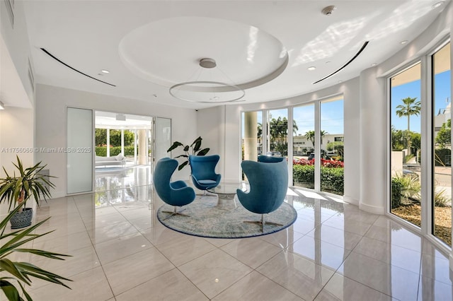 sitting room with a tray ceiling, light tile patterned floors, and baseboards