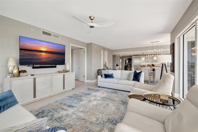 living area featuring visible vents and ceiling fan with notable chandelier