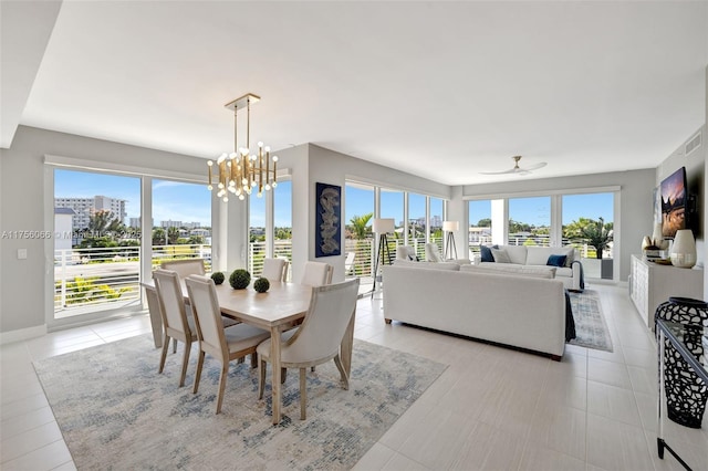 dining area with visible vents, baseboards, a city view, light tile patterned floors, and ceiling fan with notable chandelier