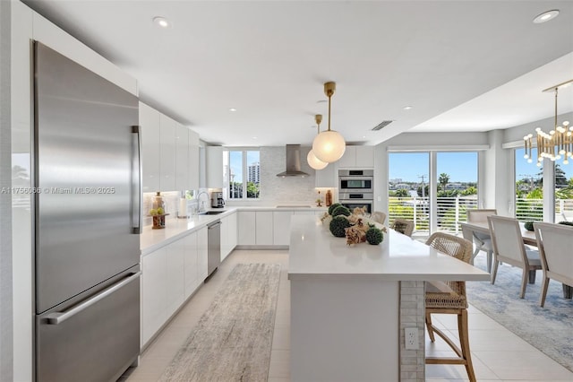 kitchen featuring light tile patterned floors, wall chimney exhaust hood, modern cabinets, visible vents, and appliances with stainless steel finishes