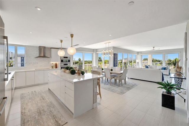 kitchen featuring tasteful backsplash, wall chimney range hood, light countertops, white cabinets, and modern cabinets