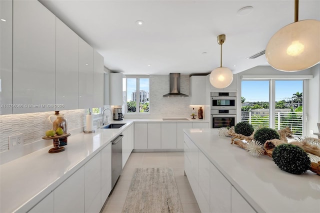kitchen with a sink, wall chimney range hood, modern cabinets, and stainless steel appliances