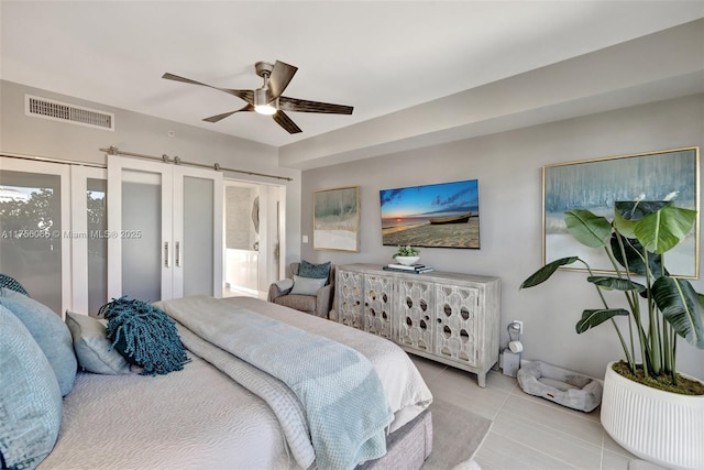 bedroom featuring tile patterned flooring, a barn door, visible vents, and ceiling fan