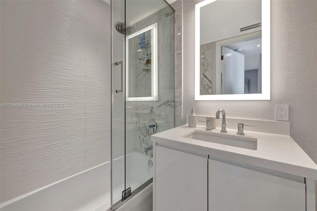 full bath with visible vents, vanity, and bath / shower combo with glass door