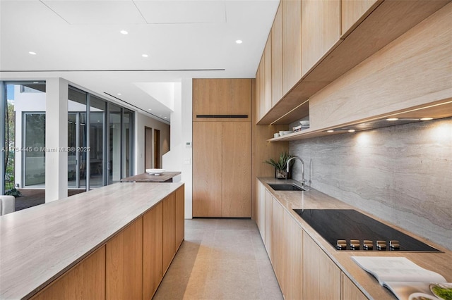 kitchen with black electric cooktop, modern cabinets, backsplash, and a sink