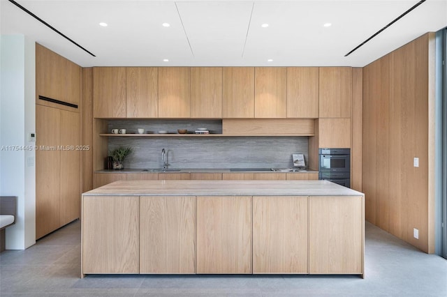 kitchen featuring a center island, modern cabinets, light brown cabinets, and a sink