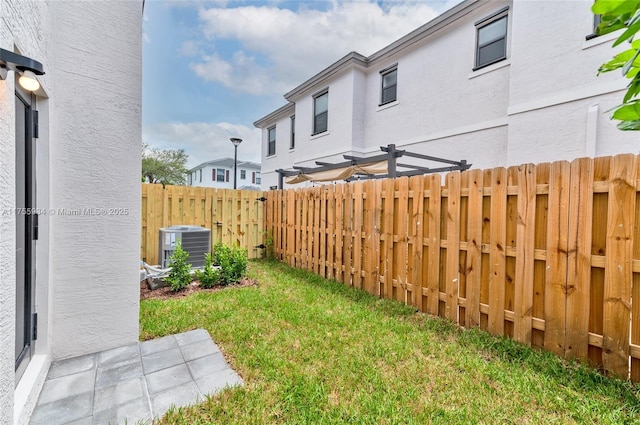 view of yard with central AC and fence