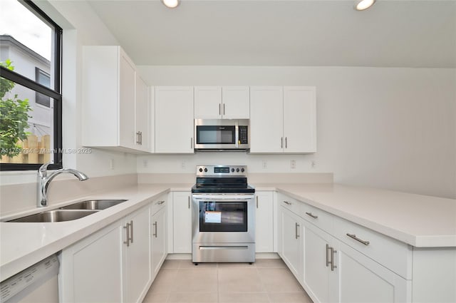 kitchen featuring light tile patterned floors, appliances with stainless steel finishes, white cabinets, and a sink