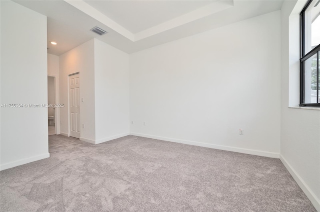 carpeted spare room with baseboards, visible vents, a raised ceiling, and recessed lighting