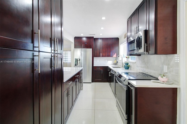 kitchen with light tile patterned floors, stainless steel appliances, light countertops, decorative backsplash, and a sink