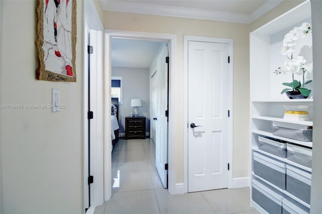 corridor featuring baseboards, ornamental molding, and light tile patterned flooring