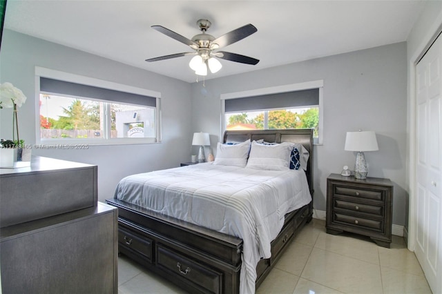 bedroom featuring light tile patterned floors, a closet, baseboards, and a ceiling fan