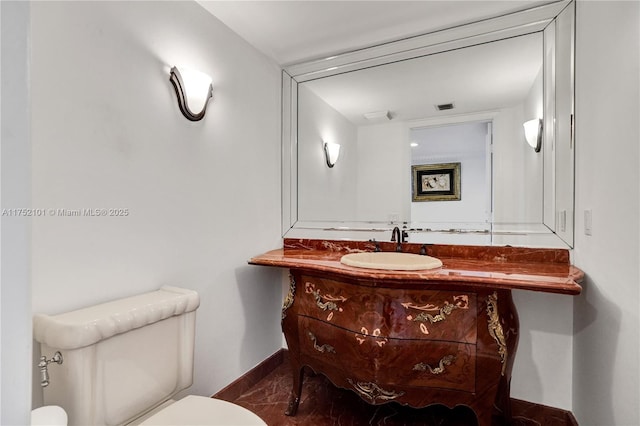 half bath with toilet, visible vents, vanity, baseboards, and marble finish floor