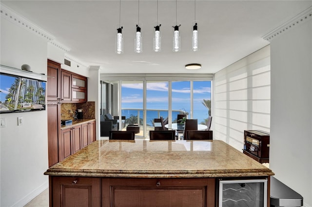 kitchen with light stone counters, a center island, decorative light fixtures, tasteful backsplash, and beverage cooler