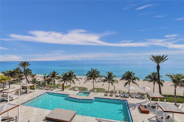 pool featuring a community hot tub, a patio area, and a water view