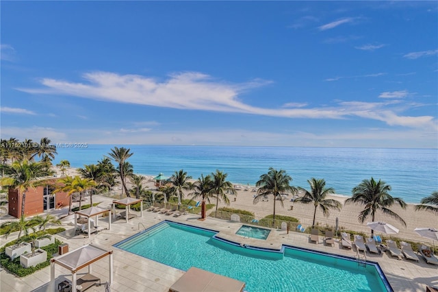 community pool with a patio, a water view, and a hot tub