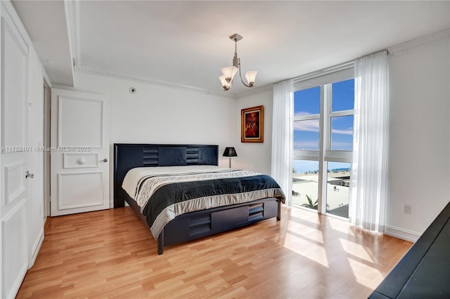 bedroom with access to exterior, floor to ceiling windows, light wood finished floors, and an inviting chandelier