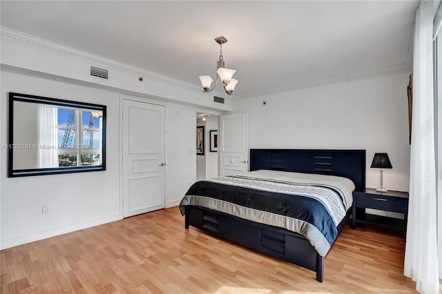 bedroom featuring baseboards, visible vents, ornamental molding, light wood-style floors, and a notable chandelier