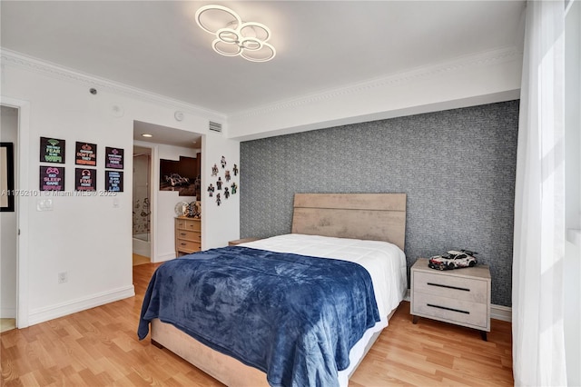 bedroom featuring an accent wall, wood finished floors, baseboards, and wallpapered walls