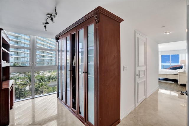 corridor with baseboards, floor to ceiling windows, and tile patterned flooring