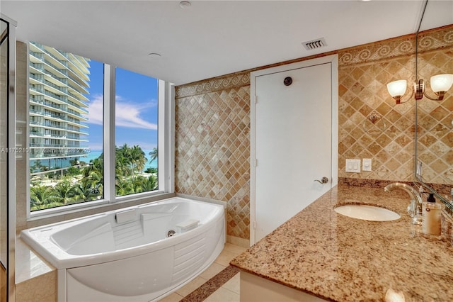 bathroom with tile walls, visible vents, vanity, tile patterned flooring, and a bath