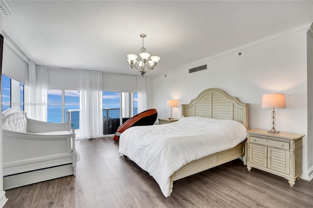 bedroom with a chandelier, a baseboard radiator, visible vents, and wood finished floors