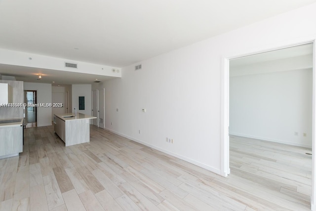 kitchen with a kitchen island with sink, a sink, visible vents, light wood-style floors, and modern cabinets