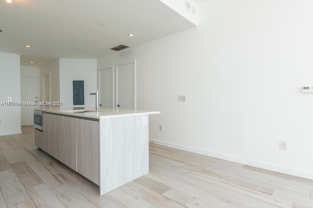 kitchen with a large island, visible vents, light wood-style flooring, a sink, and modern cabinets