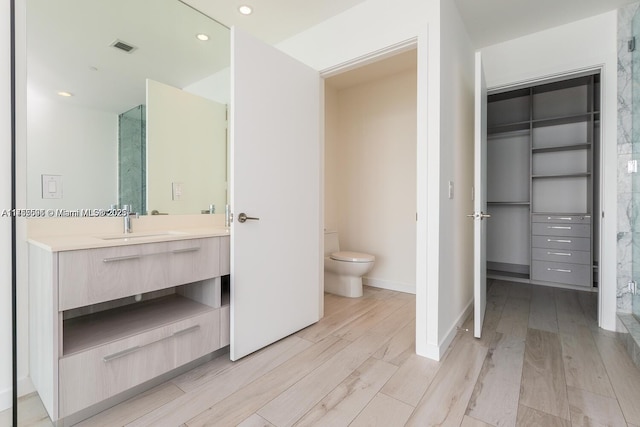 full bath with toilet, wood finished floors, visible vents, vanity, and baseboards