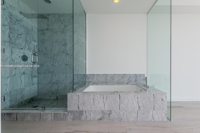 bathroom with a garden tub, a marble finish shower, and wood finished floors