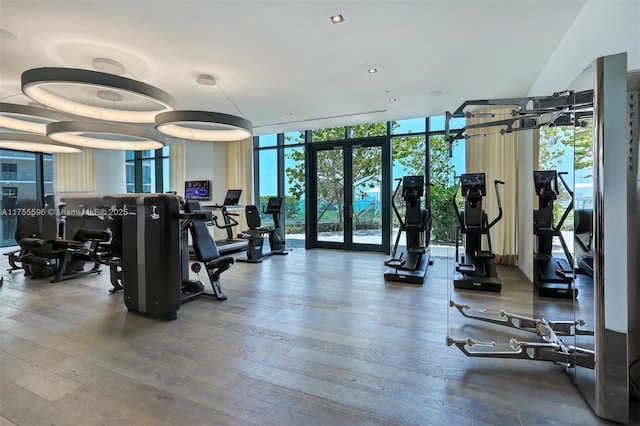 workout area with a wall of windows, wood finished floors, and french doors