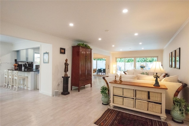 living area with baseboards, ornamental molding, recessed lighting, and light wood-style floors