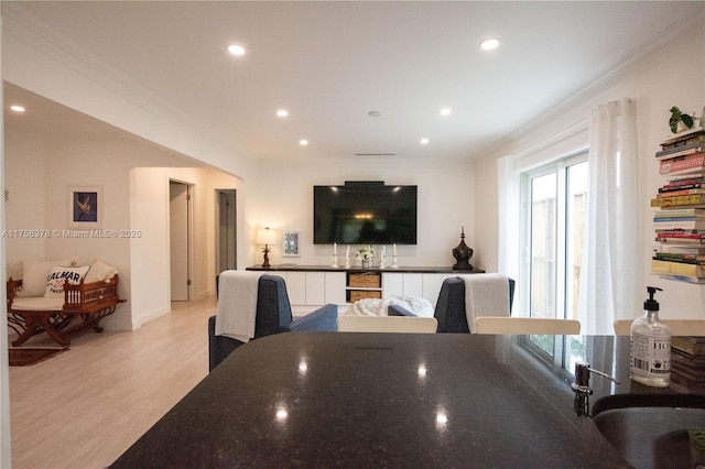 interior space featuring dark stone countertops, crown molding, light wood-style flooring, and a sink